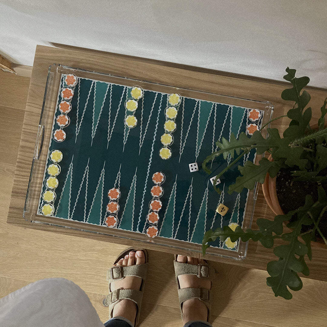 Plateau de backgammon vert posé sur une table basse en bois, vu du dessus