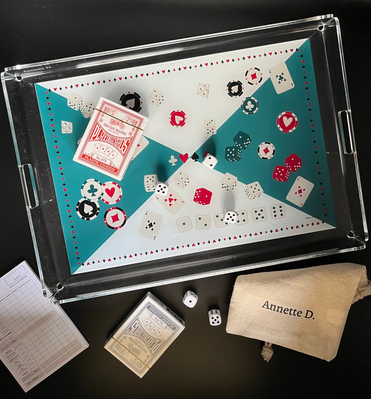Plateau de jeu en plexi à fond turquoise et blanc, garni de cartes, de dés et de jetons de poker