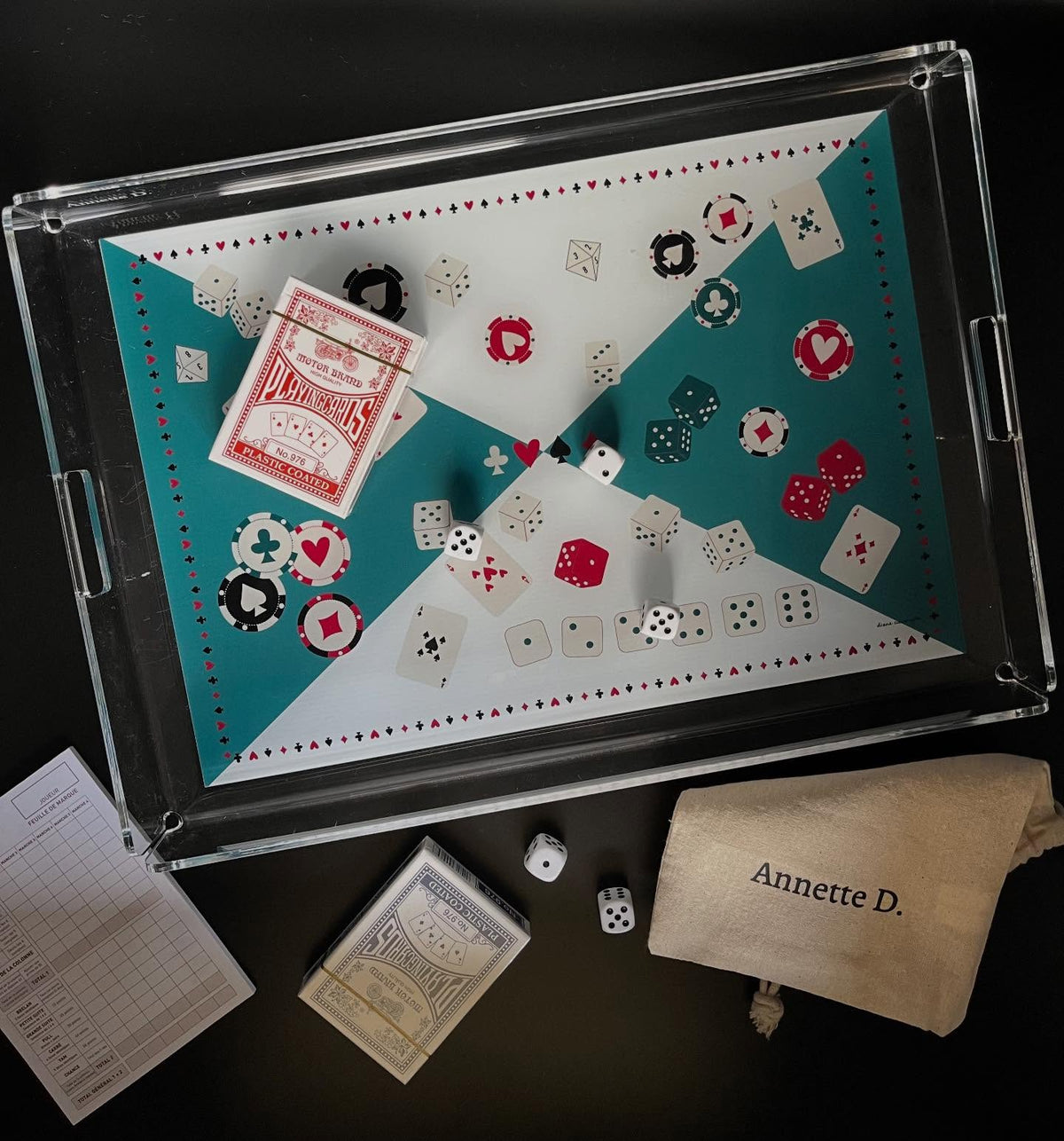 Plateau de jeu vert et blanc avec jetons, dés, jeu de cartes et pochette en tissu Annette D., sur fond noir