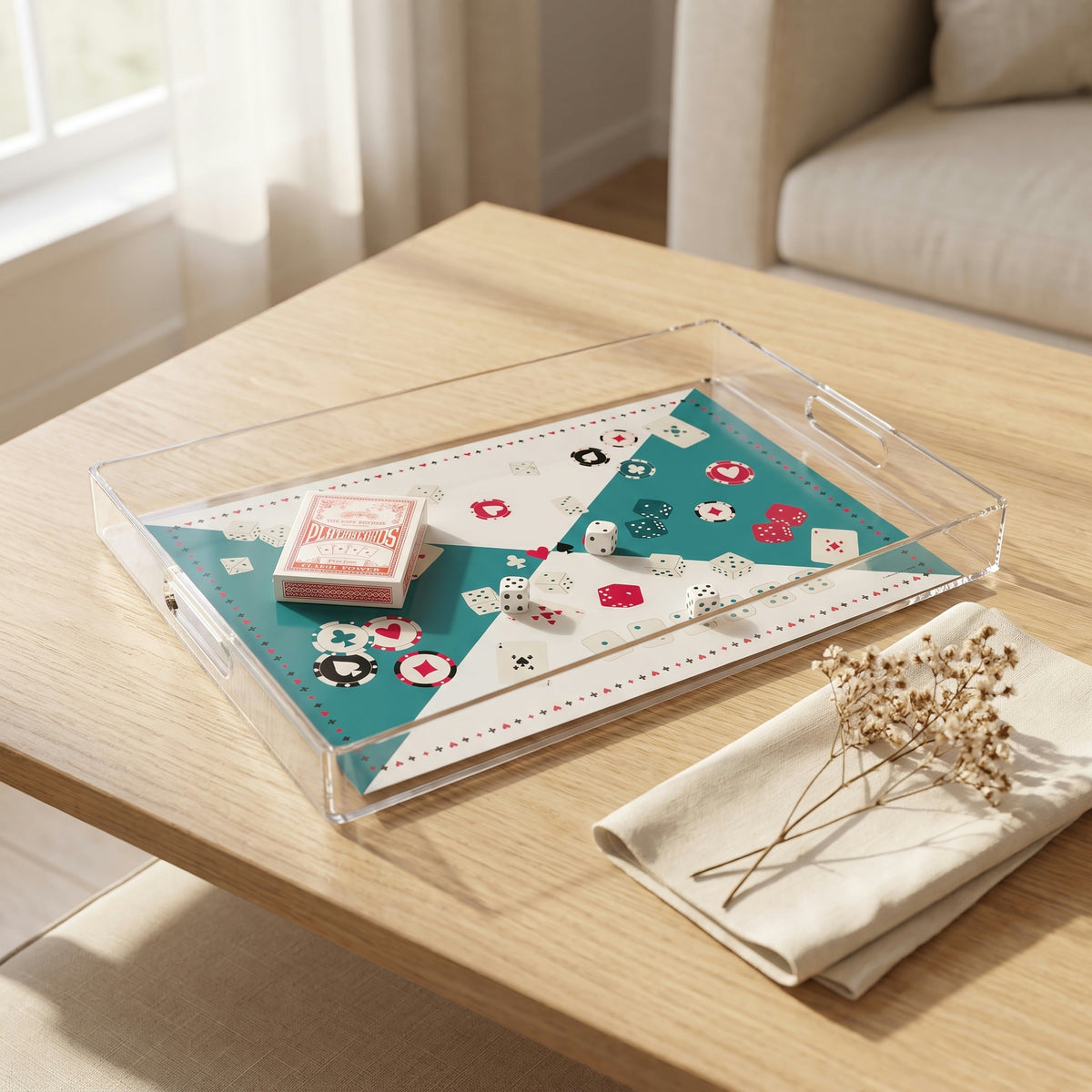 Plateau de jeux en plexi imprimé de cartes, de jetons et de dés sur fond bleu canard et blanc, posé sur une table en chêne clair avec une serviette en lin